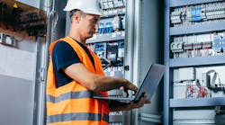 Adult electrician builder engineer testing and screwing equipment in fuse box and repairing of modern electricity power station