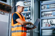 Adult electrician builder engineer testing and screwing equipment in fuse box and repairing of modern electricity power station Adult electrician builder engineer testing and screwing equipment in fuse box and repairing of modern electricity power station