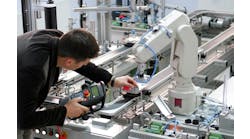 Man is holding teach panel to control a robotic arm, which is integrated on smart factory production line Man is holding teach panel to control a robotic arm, which is integrated on smart factory production line