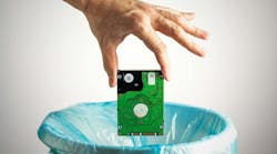 Person's hand throws a computer hard disk into the trash bin