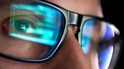 Focused developer coder wears glasses working on computer looking at programming code Focused developer coder wears glasses working on computer looking at programming code