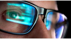 Focused developer coder wears glasses working on computer looking at programming code